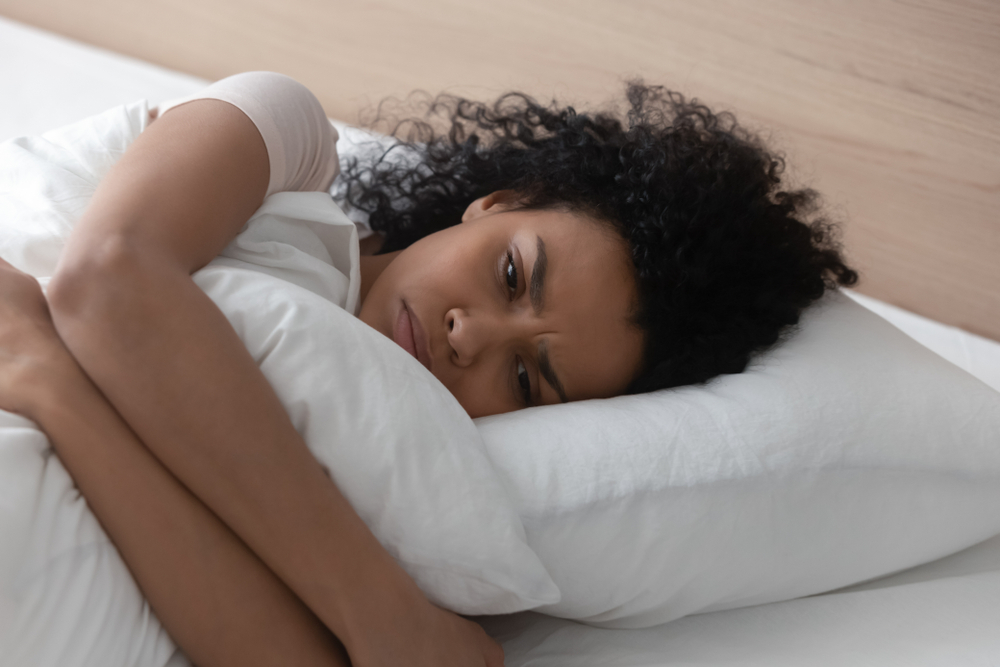 woman laying in bed looking sad.